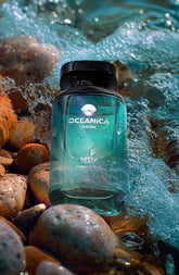 Oceanica perfume bottle on pebbles with water splashes